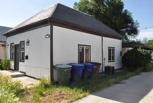 View of property exterior featuring cooling unit and a shingled roof