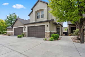 View of front of house with stone siding, stucco siding, and concrete driveway