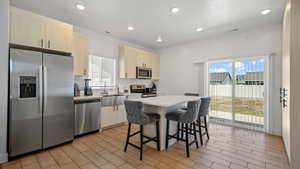 Kitchen with appliances with stainless steel finishes, a sink, a breakfast bar area, a center island, and light countertops