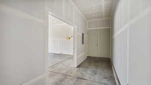 Hallway with unfinished concrete flooring and electric panel