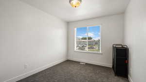 Empty room with baseboards and dark carpet