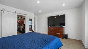 Carpeted bedroom with baseboards, a spacious closet, a barn door, recessed lighting, and a closet