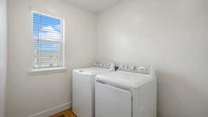 Laundry area featuring independent washer and dryer, baseboards, and wood finished floors