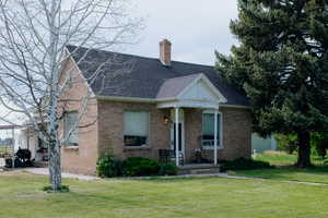 View of front of property with a front lawn, a chimney, and brick siding