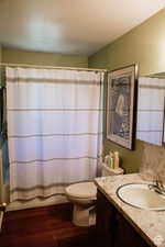 Bathroom featuring vanity, wood finished floors, toilet, and shower / bath combination with curtain