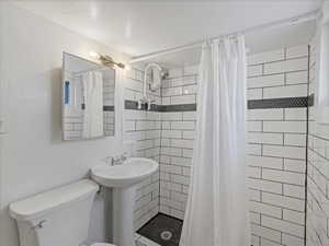 Full bath with toilet, a stall shower, and a sink