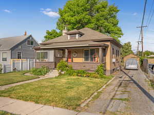 Bungalow-style house featuring asphalt driveway, a shingled roof, a porch, and brick siding