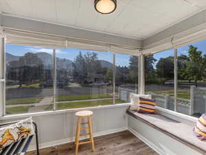 Sunroom / solarium with wood finished floors, a mountain view, and baseboards