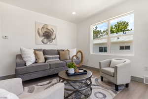 Living room with light wood-style flooring, baseboards, and recessed lighting