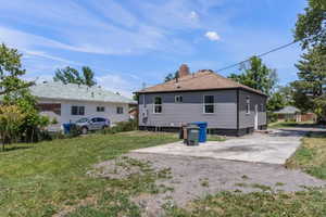 Rear view of house with a chimney and a lawn
