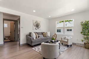 Living room with light wood finished floors, recessed lighting, and baseboards