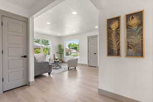 Foyer entrance with a textured ceiling, baseboards, recessed lighting, and light wood-style flooring