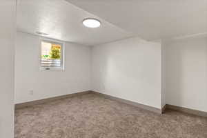 Unfurnished room with carpet floors, a textured ceiling, and baseboards