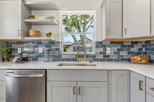 Kitchen featuring dishwasher, a sink, tasteful backsplash, light countertops, and gray cabinets