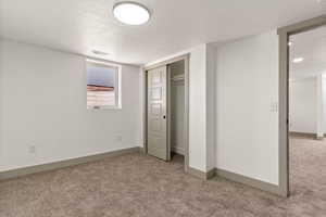 Unfurnished bedroom featuring carpet, a textured ceiling, a closet, and baseboards