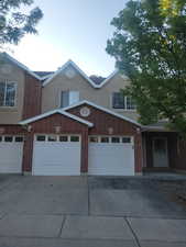 View of front of property featuring concrete driveway, a garage, stucco siding, and brick siding