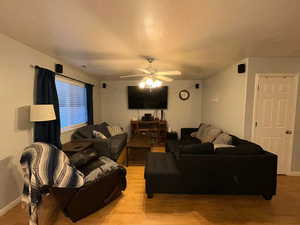 Living room featuring ceiling fan, baseboards, and light wood finished floors