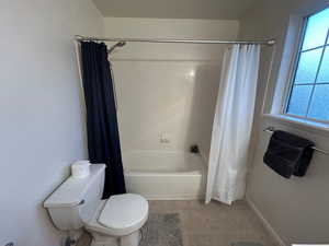 Bathroom with toilet, shower / bath combo with shower curtain, tile patterned flooring, and baseboards