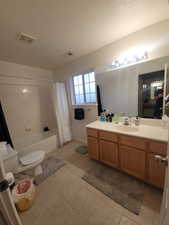 Full bath with vanity, toilet, tile patterned flooring, shower / tub combo, and a textured ceiling