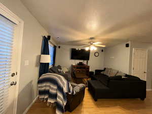 Living area with a ceiling fan, baseboards, and light wood-style floors