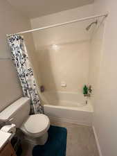 Full bath featuring toilet, shower / bathtub combination with curtain, tile patterned floors, vanity, and baseboards