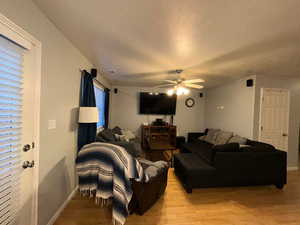 Living room featuring a ceiling fan, light wood-type flooring, and baseboards