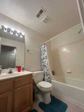 Full bath featuring toilet, tile patterned flooring, vanity, shower / bath combination with curtain, and a textured ceiling
