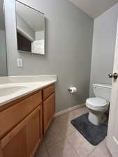 Bathroom with toilet, vanity, tile patterned floors, a textured ceiling, and baseboards