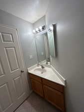 Bathroom featuring a textured ceiling, tile patterned floors, and vanity