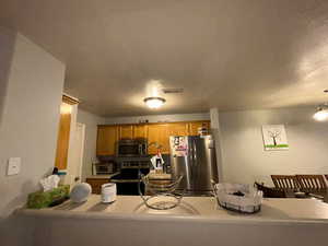 Kitchen featuring stainless steel appliances, brown cabinetry, and light countertops