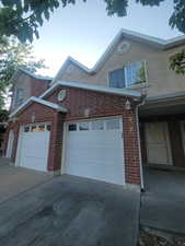 View of side of home featuring concrete driveway, brick siding, and an attached garage