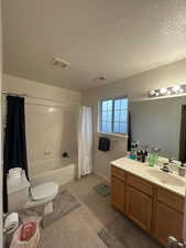Bathroom featuring toilet, vanity, shower / tub combo, tile patterned flooring, and a textured ceiling