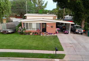 View of front of house featuring driveway, brick exterios, and an attached carport