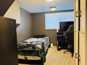 Bedroom four with carpet floors, a desk, and a textured ceiling