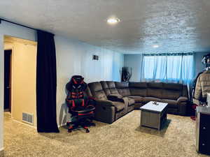 Living room with carpet, baseboards, a textured ceiling, and recessed lighting