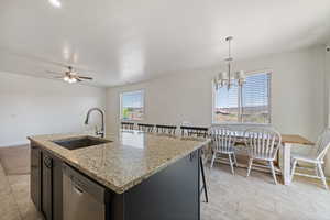 Kitchen featuring dishwasher, a sink, a kitchen island with sink, ceiling fan, and baseboards