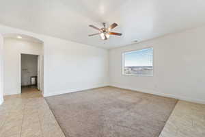 Empty room with arched walkways, a ceiling fan, and baseboards
