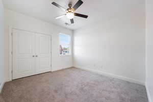 Unfurnished bedroom with carpet flooring, a closet, baseboards, and ceiling fan