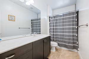 Full bathroom featuring toilet, vanity, tile patterned flooring, and a shower with curtain