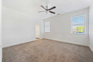 Empty room with light colored carpet, baseboards, and ceiling fan