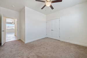 Unfurnished bedroom featuring carpet flooring, baseboards, a ceiling fan, and a closet