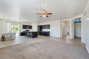 Living area with a ceiling fan, arched walkways, light carpet, and baseboards