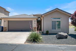 View of front of house featuring an attached garage, driveway, stucco siding, and a tile roof
