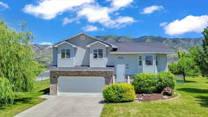 View of front of property featuring driveway, a front lawn, brick siding, an attached garage, and a mountain view