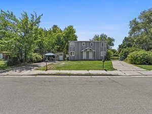 View of property with concrete driveway and a front lawn