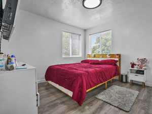 Bedroom featuring a textured ceiling, wood finished floors, and baseboards