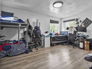 Bedroom with a textured ceiling and wood finished floors