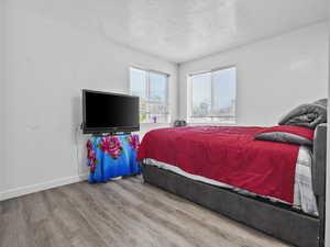 Bedroom with wood finished floors, a textured ceiling, and baseboards