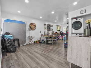 Misc room featuring stacked washer / dryer, recessed lighting, wood finished floors, and a textured ceiling