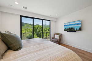 Bedroom with wood finished floors, baseboards, recessed lighting, and access to outside
